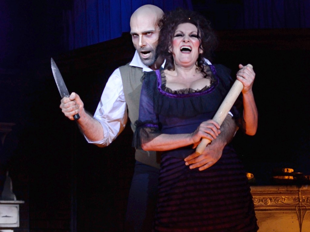 A scene from a theatrical performance featuring a man holding a knife and a woman wielding a rolling pin, both expressing intense emotions in a dramatic setting.